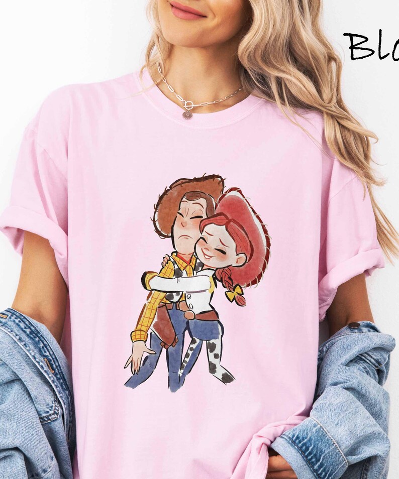 A woman wearing a pink t-shirt with a cartoon character from the Toy Story movie hugging another character.