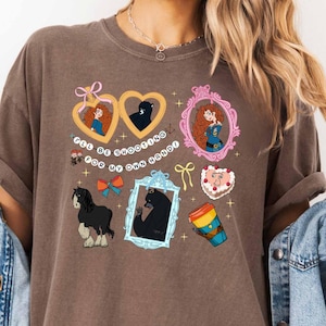 May include: Brown t-shirt with various cartoon illustrations. The shirt features images of a bear, a horse, and a character with red hair. Text on the shirt reads "I'll be shooting for my own hand."