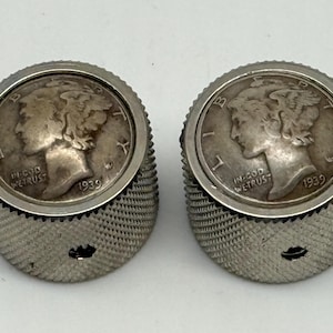 Op de afbeelding: Een paar vintage manchetknopen met 1939 Mercury dimes in getextureerd zilverkleurig metaal. Elke manchetknop toont het profiel van een vrouw en de woorden "IN GOD WE TRUST". Een uniek accessoire voor een formele gelegenheid.