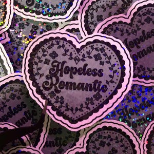 Pegatina holográfica de vinilo con forma de corazón de "Romántico desesperado"