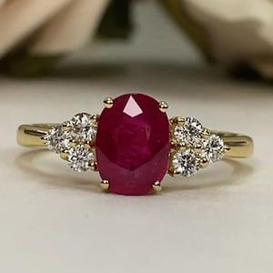 May include: A set of three ceramic mugs with a speckled, cream-colored glaze. Each mug features a different hand-painted design: a green leaf, a blue flower, and a yellow sun. The mugs have a simple, modern design.