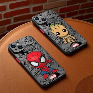 Puede incluir: Dos fundas para teléfono con personajes de Marvel. Una funda muestra a Spider-Man en rojo y azul, la otra a Groot. Ambas fundas tienen un fondo gris con ilustraciones estilo cómic y el logo de Marvel.