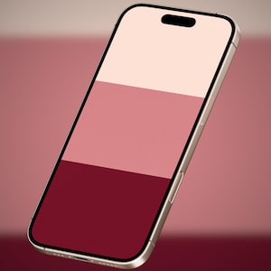 Könnte beinhalten: Ein Smartphone mit einem hellen Metallrahmen und einem schwarzen Rand. Der Bildschirm zeigt eine vertikale dreifarbige Grafik mit drei horizontalen Farbbändern: ein blass cremefarbener oberer Teil, ein gedeckter rosafarbener Mittelteil und ein tiefburgunderroter unterer Teil.