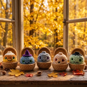 May include: Five small, round, crocheted figures sit in individual tan crocheted baskets. The figures include a yellow and orange candy corn, a blue creature with a purple hat, a grey mummy, a beige mummy, and a green monster with black stitches.