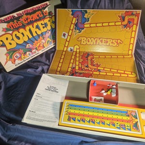 May include: Vintage "Bonkers!" board game with a yellow game board and box. The box lid features the game title in large, colorful letters. The game board has a track with numbered spaces and various game pieces.