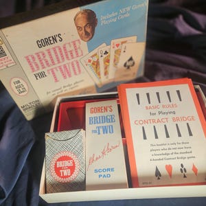 May include: Vintage "Goren's Bridge for Two" card game set. The box features the game title, a portrait, and the text "Includes NEW Goren's Playing Cards." Inside, there's a deck of cards, score pad, and a booklet titled "Basic Rules for Playing Contract Bridge."