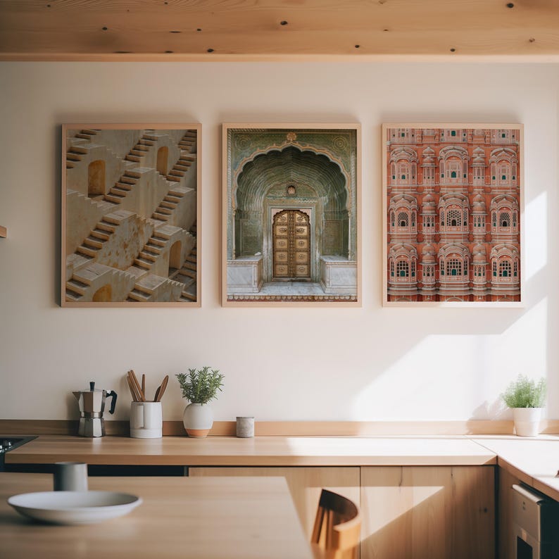 Op de afbeelding: Drie ingelijste wandkunstwerken op een rij. De linker print toont geometrische stenen trappen. De middelste print toont een sierlijke boogdeur met ingewikkeld houtsnijwerk. De rechter print toont een rode gevel met veel kleine ramen.