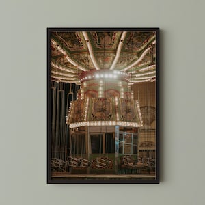 May include: A framed photograph of a vintage carousel ride at night. The carousel is lit with warm, inviting lights, and the details of the ride's ornate design are visible. The image evokes a sense of nostalgia and amusement.