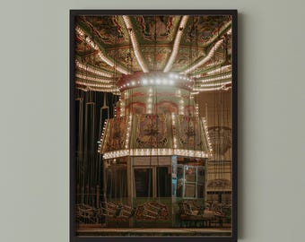 May include: A framed wall art print featuring a vintage-style carousel at night. The ride is illuminated by numerous small warm white light bulbs, highlighting the green and gold decorative panels and the hanging swing seats suspended by chains.