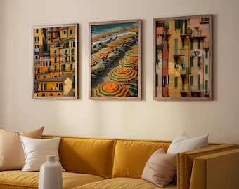 Op de afbeelding: Drie ingelijste wandkunstwerken op een rij. De linker- en rechterafbeeldingen tonen gele en oranje gebouwen van meerdere verdiepingen met groene luiken. De middelste afbeelding toont een strand met rijen oranje en groen gestreepte parasols.
