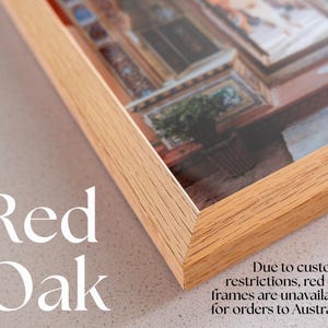 Op de afbeelding: Een lichtgekleurde fotolijst van rood eikenhout met een verstekverbinding. De lijst bevat een foto van een interieur met een kamerplant. De tekst Red Oak staat links afgedrukt en rechts staat een mededeling over douanebeperkingen.