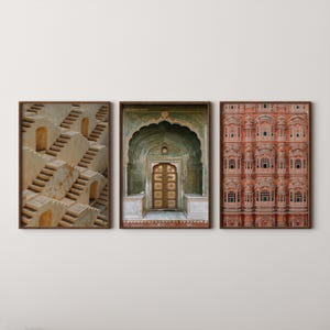 Op de afbeelding: Een set van drie ingelijste wandkunstprints. De linker print toont beige stenen trappenputten. De middelste print toont een groene boogdeur met een gouden deur. De rechter print toont een rode gevel met meerdere kleine boogramen.