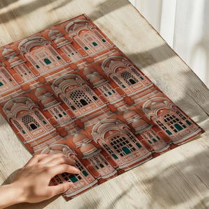 Op de afbeelding: Een rechthoekige placemat met een herhalend patroon van terracotta-kleurige architecturale structuren met boogramen, koepeldaken en gedetailleerde witte versieringen. Het ontwerp bevat kleine blauwgroene accenten in de raamkozijnen.