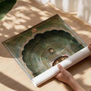 Op de afbeelding: Een opgerolde papieren print met een gedetailleerde architecturale illustratie van een groene boogingang met ingewikkelde patronen en een centrale deur. Het kunstwerk toont een reeks concentrische, geschulpte treden die naar een terugliggende ingang leiden.