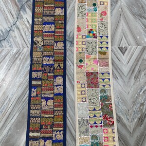 May include: Two rectangular, patchwork textile runners. One has a navy blue border and features squares of gold, red, and blue patterns. The other has an off-white border and features squares of various colors and patterns.