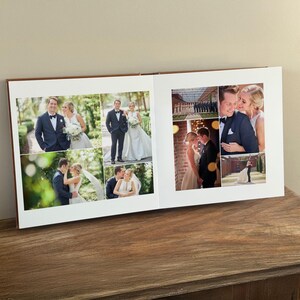 May include: An open photo album featuring a collection of wedding photographs printed on white pages. The images display a couple in formal attire, including a dark suit and a white gown, captured in various outdoor and indoor settings.