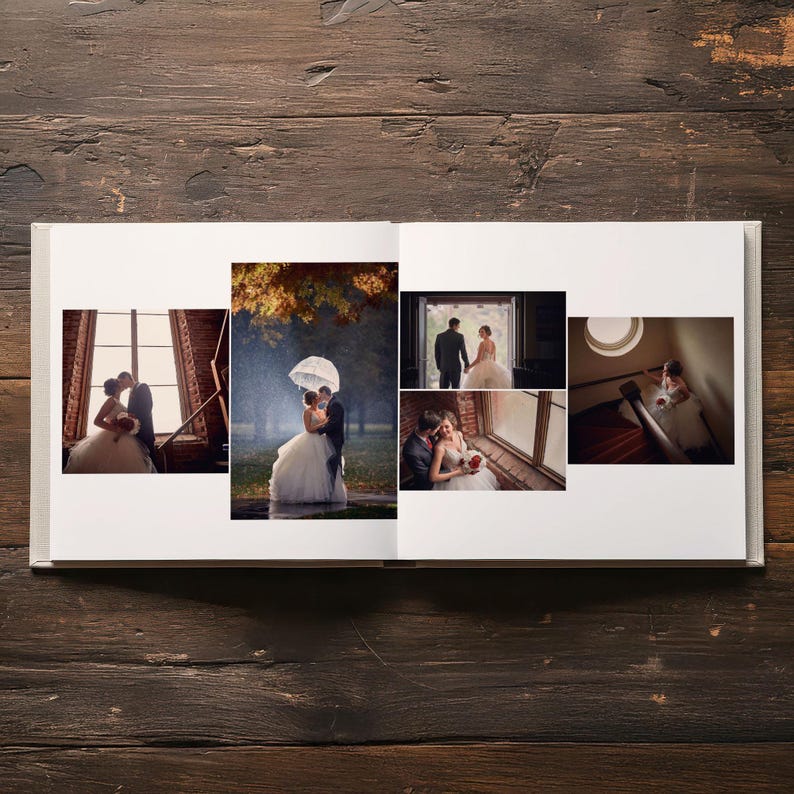 May include: An open photo album featuring five distinct wedding photographs displayed on white pages. The images show a couple in formal attire, including scenes of them standing by a window, under an umbrella in the rain, and on a staircase.