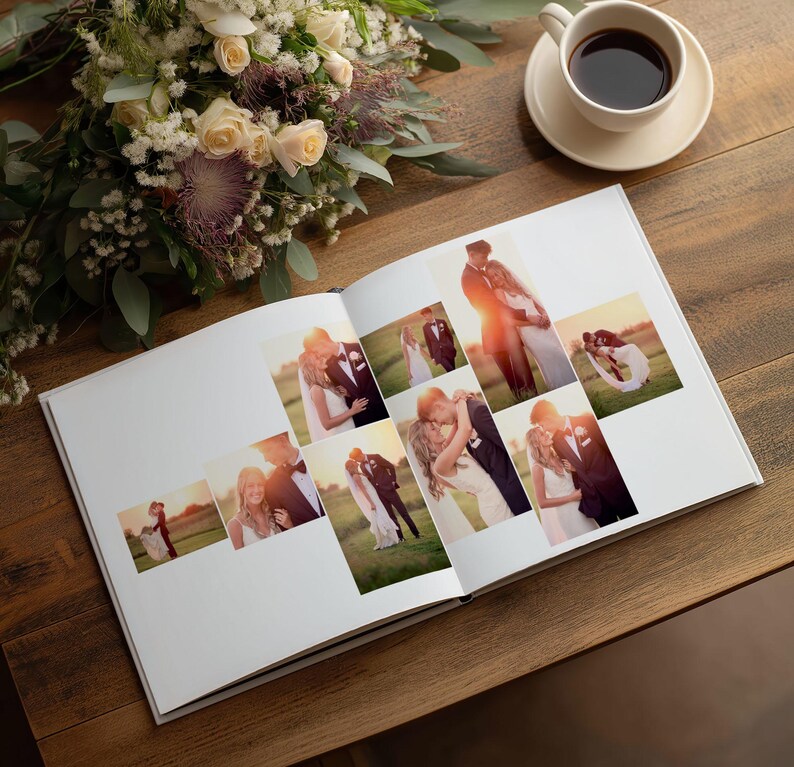 May include: An open photo album featuring a collection of wedding photographs displayed on white pages. The album is placed next to a bouquet of cream and purple flowers and a white ceramic cup filled with dark coffee on a wooden surface.