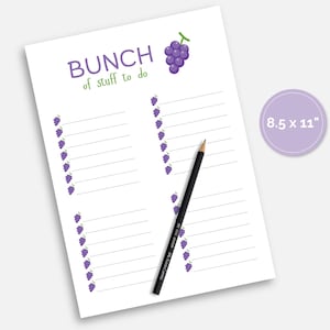 May include: A white 8.5 x 11 inch notepad with the words "BUNCH of stuff to do" in purple and green. The notepad has a grape illustration and lined sections for notes. A black pencil rests on the notepad.