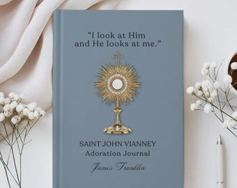 May include: A slate blue hardback journal featuring a gold monstrance illustration in the centre. The text reads: I look at Him and He looks at me. Saint John Vianney Adoration Journal, and the name James Franklin in a cursive script font.