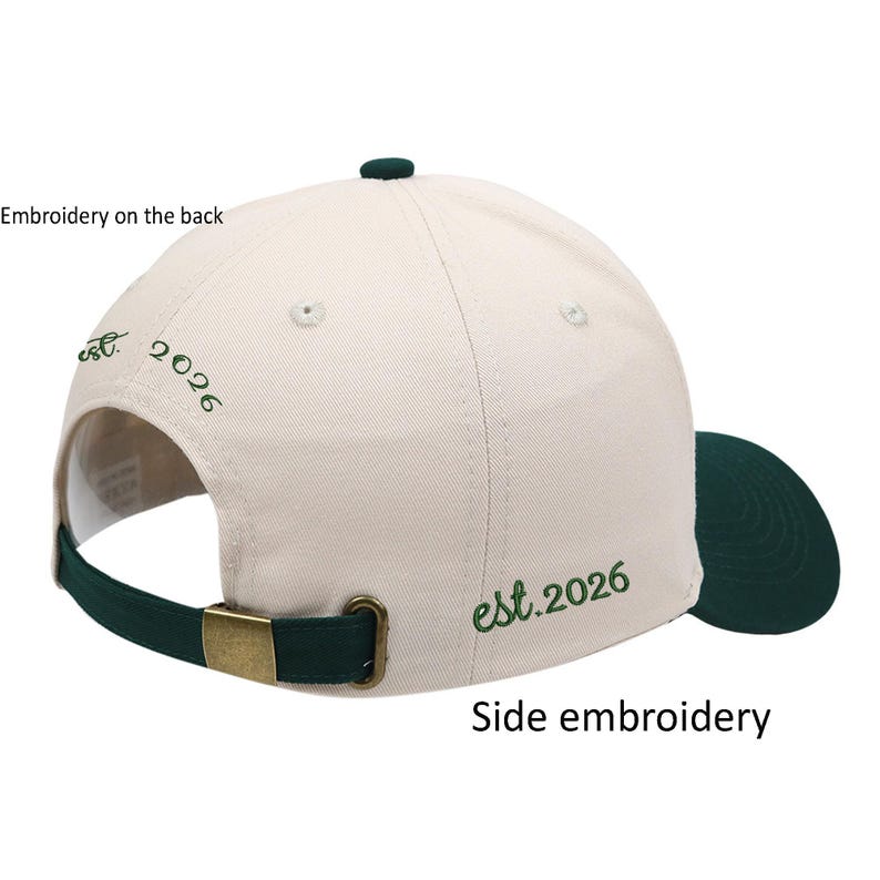 Op de afbeelding: Een cr&egrave;mekleurige baseballpet met een donkergroene klep en bijpassend groen borduursel aan de zijkant en achterkant met de tekst "est. 2026". De pet heeft een donkergroene verstelbare band met een messingkleurige metalen gespsluiting.