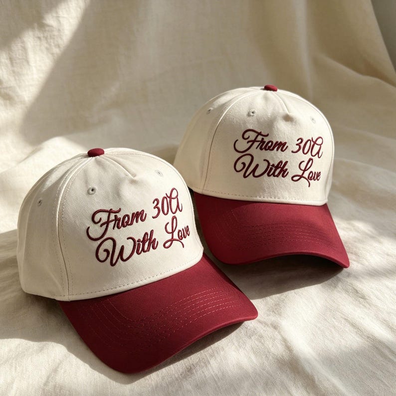 Pode incluir: Dois bon&eacute;s de beisebol com copa cor de creme e aba vermelho-escura. Cada bon&eacute; tem o texto bordado "From 30A With Love" em letra cursiva vermelho-escura no painel frontal. Os bon&eacute;s possuem um bot&atilde;o no topo e ilh&oacute;s costurados.