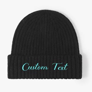 Può includere: Berretto in maglia a coste nero con la scritta ricamata "Custom Text" in turchese. Il berretto è uno stile classico, perfetto per il freddo. Il cappello è realizzato in un materiale morbido e caldo.
