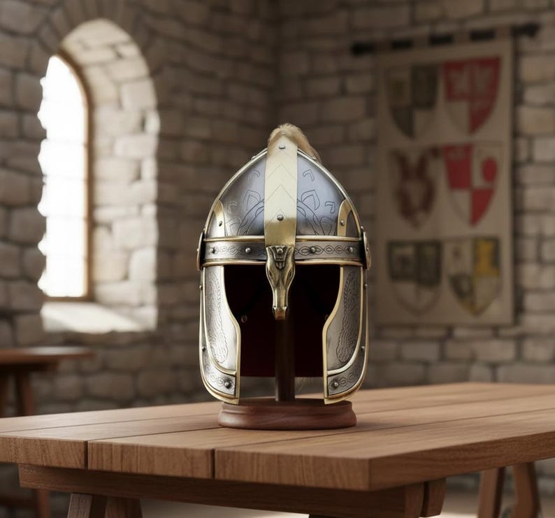 May include: A detailed, antique-style helmet with a silver and gold finish, displayed on a wooden stand. The helmet features intricate designs and a decorative gold accent on the front. The background includes a wooden table and a stone wall.