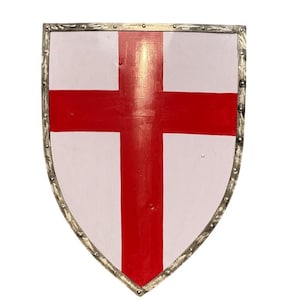 Könnte beinhalten: Ein Schild in Heizkörperform mit weißer Oberfläche und einem kräftigen roten Kreuz, das vertikal und horizontal zentriert ist. Der Schild ist von einem metallischen Rand mit sichtbaren Nieten umgeben, die gleichmäßig entlang der Außenkante verteilt sind.