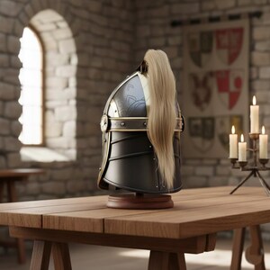 May include: A black and gold medieval helmet with a blonde plume, displayed on a wooden table. The helmet features decorative metal accents and is set against a stone wall background. A candle holder with lit candles is to the right.