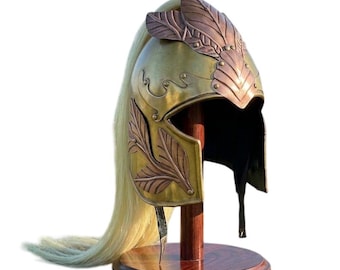 May include: A brass helmet featuring copper-toned leaf engravings on the crest and side panels. The helmet includes a long, flowing blonde horsehair plume attached to the back, mounted on a circular wooden stand with a central vertical support.