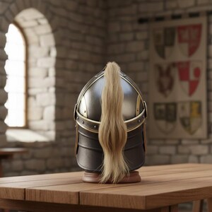 May include: A medieval-style helmet with a dark metallic finish and gold accents, featuring a long, flowing blonde plume. The helmet is displayed on a wooden table in a room with a stone wall and a banner.