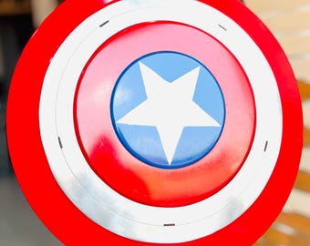 May include: A round shield with a red outer ring, a white inner ring, and a blue center. The center features a white five-pointed star. The shield is a replica of Captain America's shield.