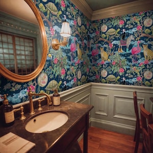 May include: A bathroom with a dark blue floral wallpaper featuring turtles, leopards, flamingos, and zebras. A gold-framed mirror hangs above a dark brown sink with gold fixtures. A wall sconce with a white shade is mounted on the wall.