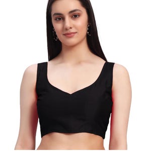 Puede incluir: Una blusa negra sin mangas con cuello en V. La blusa est&aacute; hecha de una tela oscura y lisa. La imagen es un primer plano de la blusa, que muestra el escote y la textura de la tela. La blusa es una prenda b&aacute;sica.