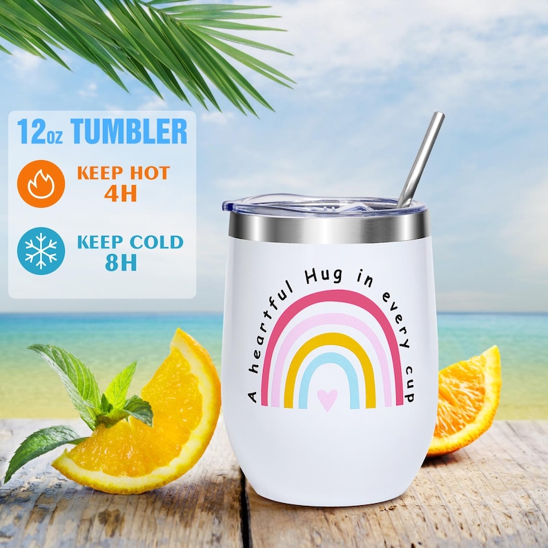 May include: White 12oz tumbler with a stainless steel rim and straw. The tumbler features a rainbow design with the text "A heartful hug in every cup." It keeps drinks hot for 4 hours and cold for 8 hours.