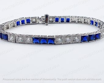 May include: A silver bracelet featuring alternating square blue and clear gemstones. The bracelet has a rectangular design with a clasp. The gemstones are set in a square pattern, offering a classic and elegant appearance.