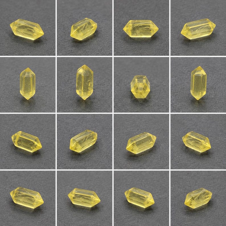 May include: A grid of yellow crystal beads. Each bead is an elongated hexagonal prism with pointed ends, displaying a translucent quality. The crystals have a faceted appearance, reflecting light. The background is a dark grey surface.