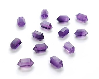 Peut inclure: Plusieurs petits cristaux d'améthyste facettés, dispersés sur une surface blanche. Chaque cristal est d'un violet profond avec de multiples facettes, reflétant la lumière. Les cristaux sont de forme hexagonale, avec des extrémités pointues.