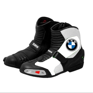 Op de afbeelding: Paar zwarte en witte motorlaarzen met het BMW-logo. De laarzen hebben een hoog ontwerp met een BMW-band. De teen heeft een zilveren accent met een rood detail.