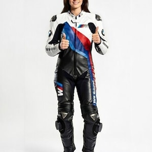 May include: A white, black, and blue BMW Motorrad motorcycle racing suit. The suit features a white upper body with blue and red accents, black leather pants, and protective knee pads. The BMW logo is visible on the chest and sleeves.