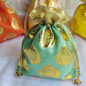 May include: A collection of drawstring gift bags in various colors, including green, orange, and yellow. The bags feature a gold floral pattern and gold ribbon closures. The bags are made of a soft fabric and are suitable for small gifts.