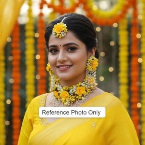 Puede incluir: Una mujer con un sari amarillo y joyas florales, incluyendo un collar, pendientes y pulseras. El fondo presenta guirnaldas decorativas amarillas y naranjas e iluminación suave. El texto "Reference Photo Only" es visible.