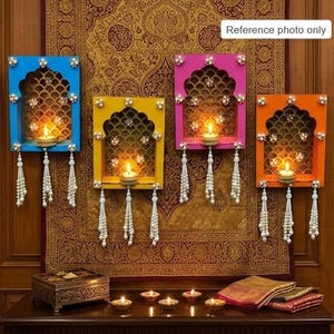 May include: Four rectangular wall-mounted shelves in blue, yellow, pink, and orange, each featuring an arched cutout, gold patterned backing, and three hanging white beaded tassels. Each shelf holds a lit tea light candle. Text reads: Reference photo only.