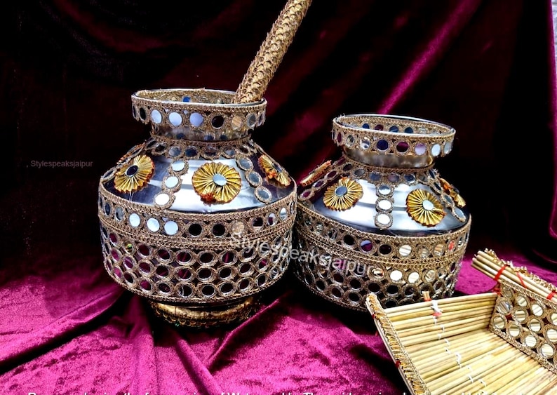 Puede incluir: Dos ollas decorativas plateadas con intrincados detalles dorados y detalles de espejo. Las ollas tienen forma redonda y est&aacute;n adornadas con dise&ntilde;os florales dorados. Un palo dorado se coloca en una de las ollas.