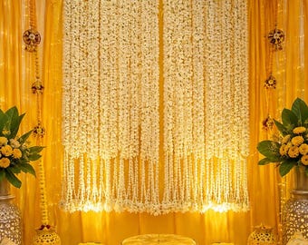 May include: A decorative backdrop featuring long, cascading white flower garlands against a bright yellow fabric curtain. The display includes a yellow cushioned seat, two bowls of yellow flowers, and two ornate lanterns with the text Reference Photo Only.