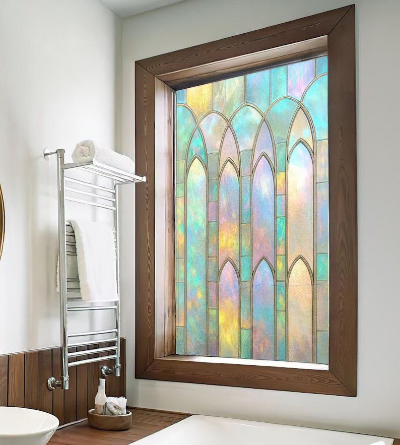 May include: A stained glass window with a wooden frame. The window features a colorful design with shades of blue, yellow, and green. The window is in a bathroom setting, with a towel rack and a wooden accent wall.