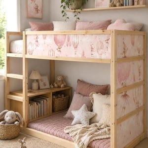 Könnte beinhalten: Ein Etagenbett aus hellem Holz mit einem rosa gemusterten Stoffpaneel, das Teddybären und Heißluftballons zeigt. Das Bett verfügt über einen unteren Schlafbereich mit rosa Bettwäsche, Kissen, einem sternförmigen Kissen und eingebauten Regalen.