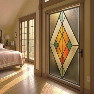 Puede incluir: Una puerta de vidriera con un dise&ntilde;o geom&eacute;trico en un dormitorio. El dise&ntilde;o presenta una gran forma de diamante con segmentos naranjas, amarillos, verdes y blancos. La puerta est&aacute; enmarcada en madera y la habitaci&oacute;n tiene pisos de madera.