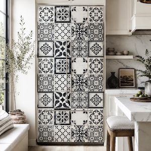 Op de afbeelding: Een hoge koelkast met dubbele deuren voorzien van een decoratieve buitenkant met een herhalend zwart-wit tegelpatroon. Het ontwerp bestaat uit diverse ingewikkelde geometrische en florale motieven die in een raster over de hele voorkant zijn geplaatst.